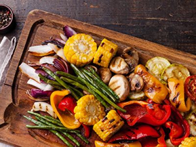 Grilled vegetables on cutting board on dark wooden background