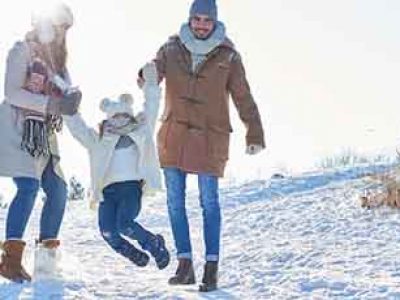 Family with child playing in the snow together in winter