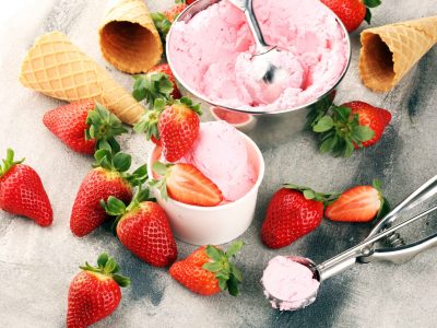 Strawberry ice cream scoop with fresh strawberries and icecream cones on a rustic background